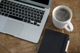 A desk with a notebook and coffee in morning light